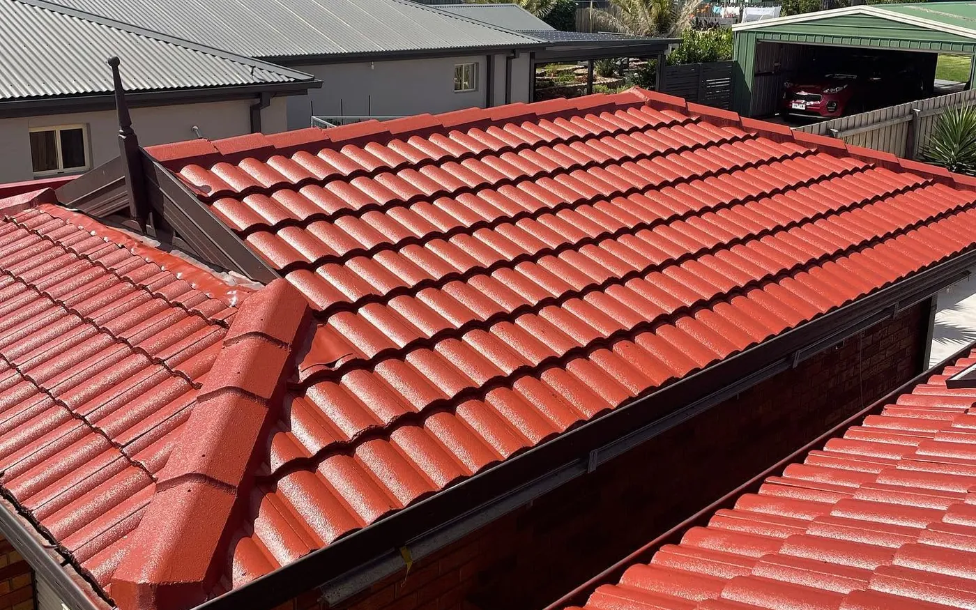 The same tiled roof after a Seaspray Restos restoration: re-pointed ridges and a glossy red membrane coating