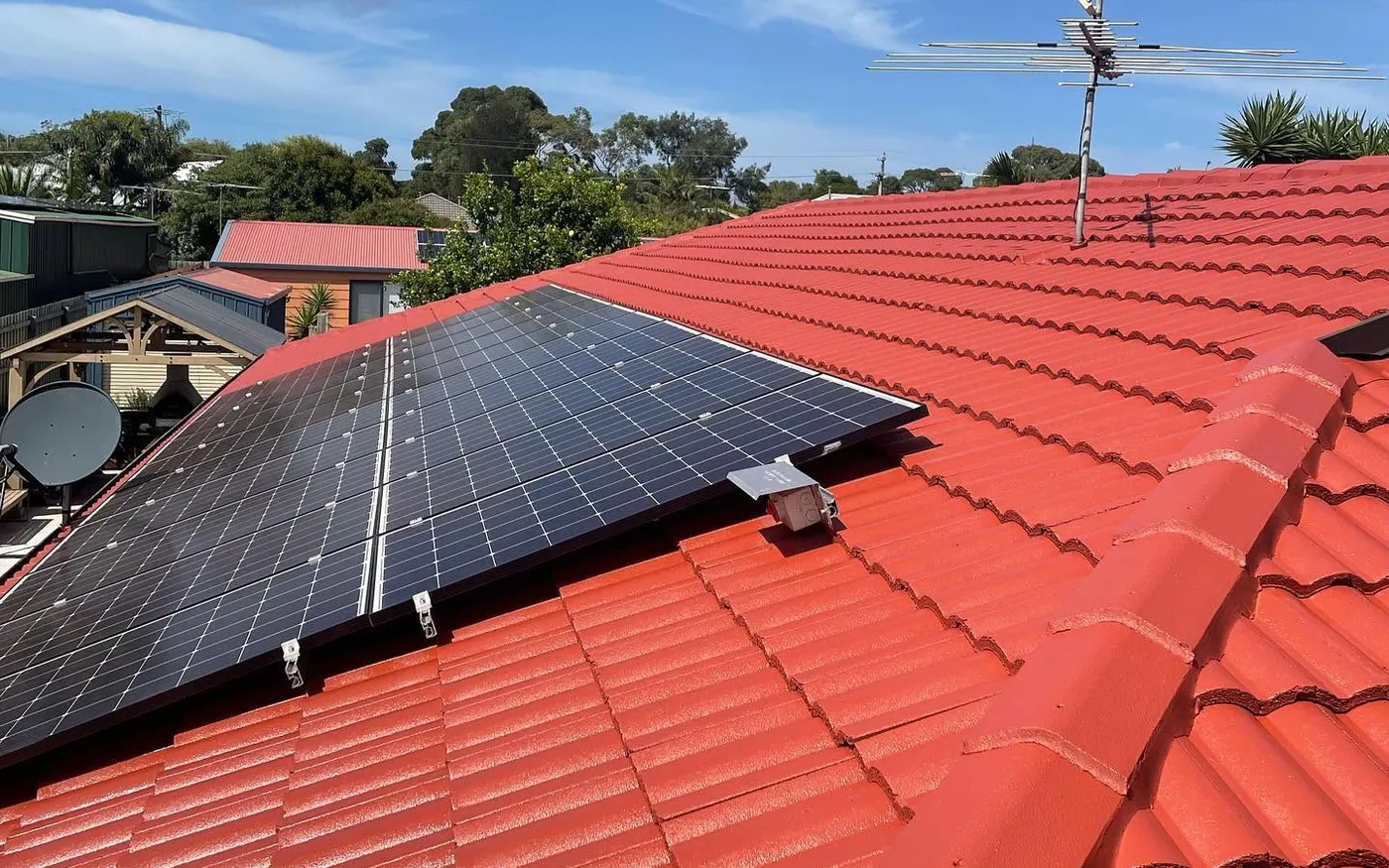Restored red tiled roof with solar panels reinstalled after coating