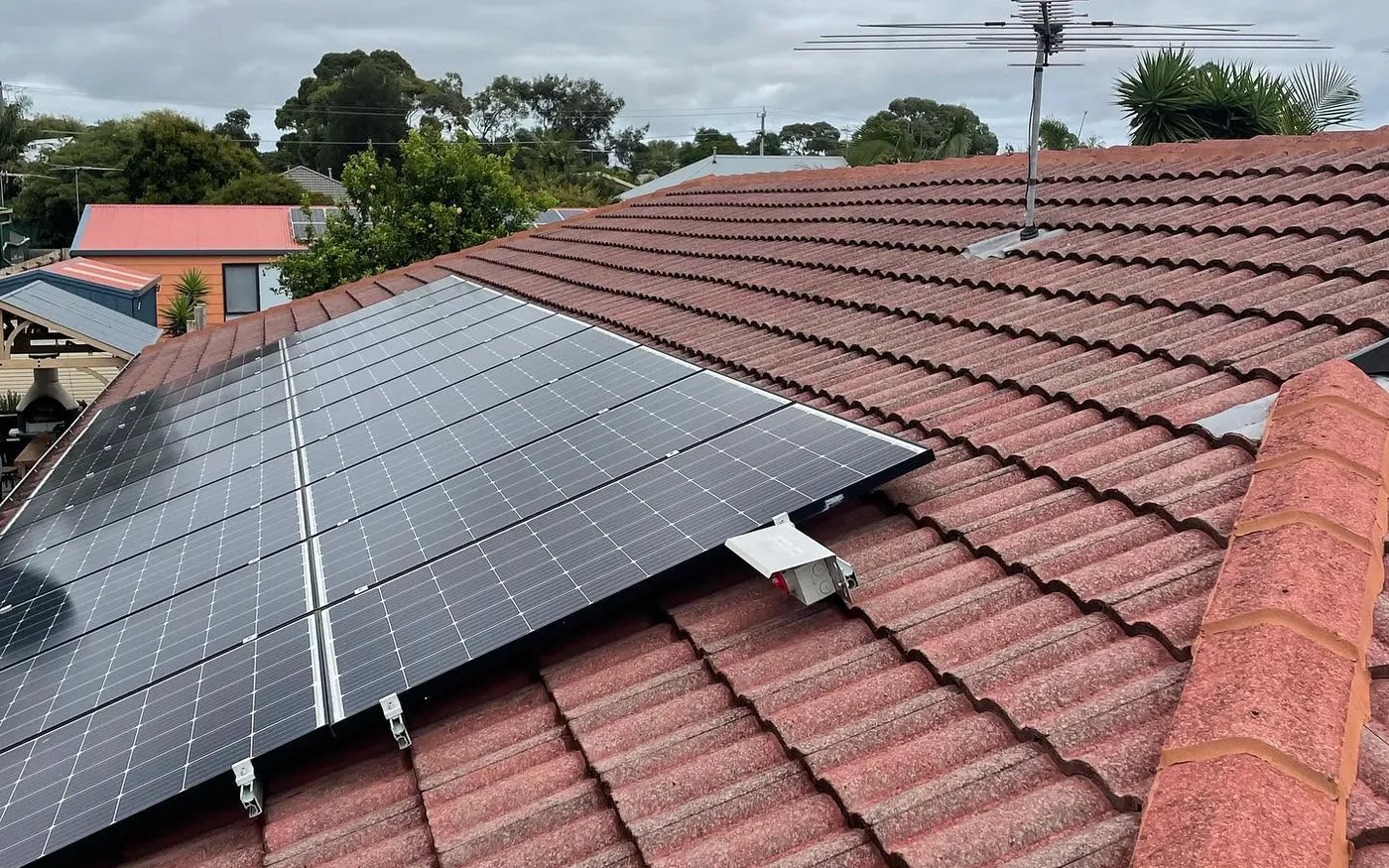 Weathered pink concrete tiles around solar panels before roof restoration